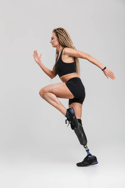 Image of an amazing healthy young disabled sportswoman isolated over grey background. Looking aside make exercises. - Φωτογραφία, εικόνα
