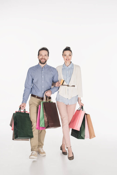 smiling couple with shopping bags and credit card isolated on white - Фото, зображення