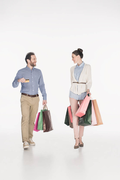 couple avec sacs à provisions et carte de crédit se regardant isolé sur blanc
 - Photo, image