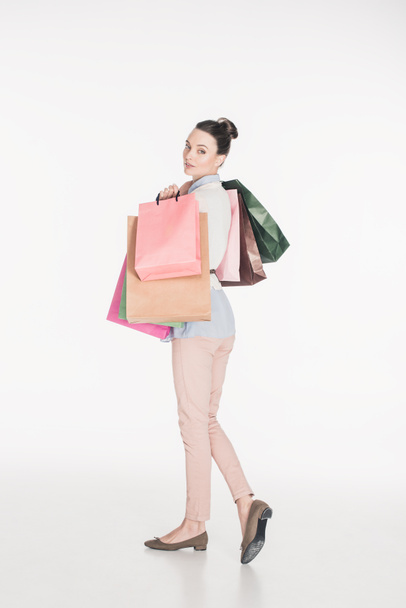 side view of stylish woman with shopping bags looking at camera isolated on white - 写真・画像