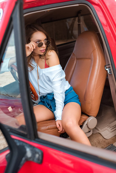 beautiful young woman in sunglasses sitting in car during trip - Photo, Image
