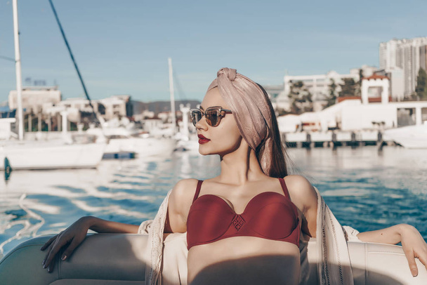 a luxurious beautiful young girl in sunglasses relaxes and rests on her yacht, sails on the Caribbean sea - Фото, зображення