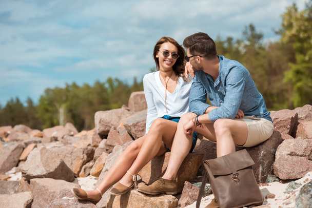 young couple sitting together on rocks outside - Фото, зображення