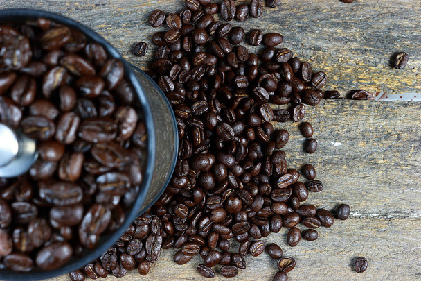 Granos de café asados en un molinillo de café a mano. Y se centran en granos de café tostados extendidos sobre un fondo de madera
. - Foto, imagen