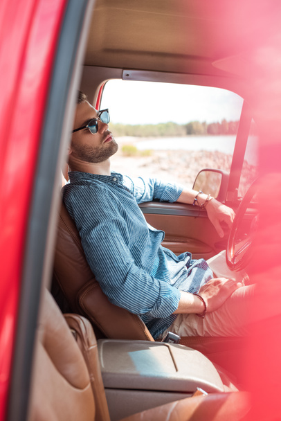 güneş gözlüğü kırmızı arabaya rahatlatıcı yakışıklı genç gezgin - Fotoğraf, Görsel