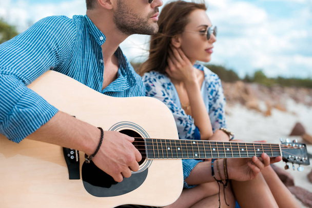 handsome man playing acoustic guitar and sitting with girlfriend - Photo, Image