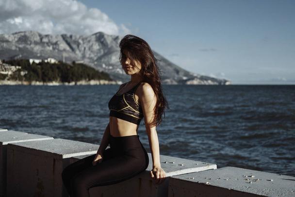 Portrait of Fit pretty smiling woman with black long hair near the sea  - Foto, Imagem