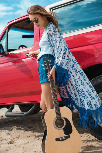 Akustik gitar kırmızı arabanın yakınında poz olan kadın - Fotoğraf, Görsel