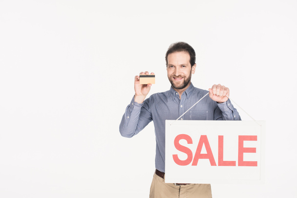 portrait of smiling man with sale card and credit card in hands isolated on white - Foto, Bild