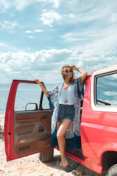 happy young woman in sunglasses standing near red car - Fotoğraf, Görsel