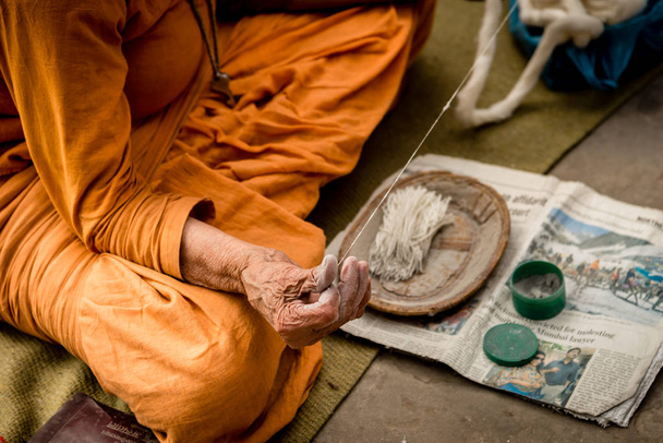 VARANASI, INDIA - FEBBRAIO 08, 2015: Una donna anziana seduta fuori, filatura a mano
. - Foto, immagini