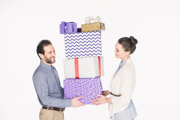 side view of smiling couple holding pile of wrapped gifts together isolated on white - Foto, immagini