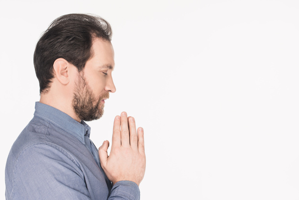 боковой вид бородатого мужчины в рубашке молящегося изолированно на белом
 - Фото, изображение