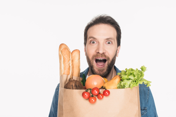 portrait of excited bearded man with paper package full of food isolated on white - Photo, Image