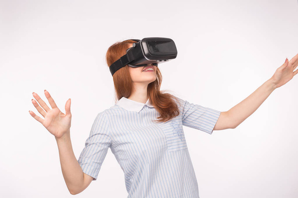 Heureuse jeune femme aux cheveux roux utilisant un casque de réalité virtuelle
 - Photo, image