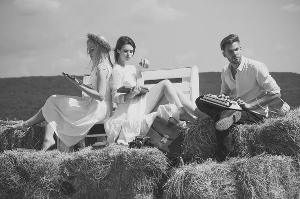 Man or macho typing on vintage typewriter on hay. Friends or students on sunny day on blue sky - Foto, immagini