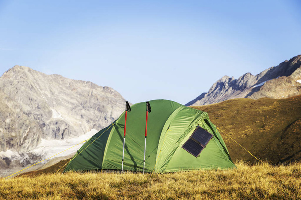 The tent is on top of the mountain. The solar panel hangs on the tent. - Foto, imagen