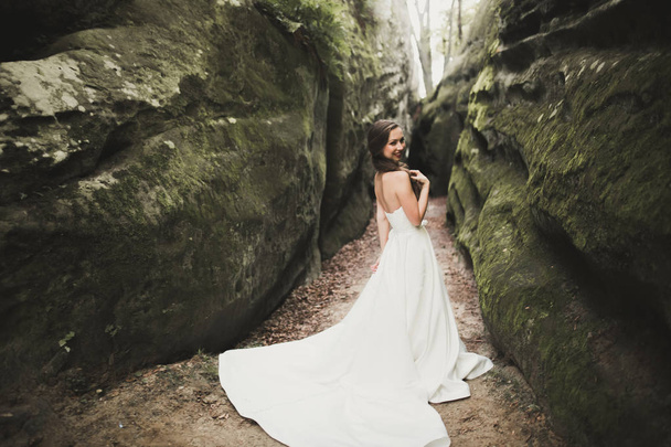 Mooie gelukkige bruid buiten in een forest met rotsen. Perfecte huwelijksdag - Foto, afbeelding