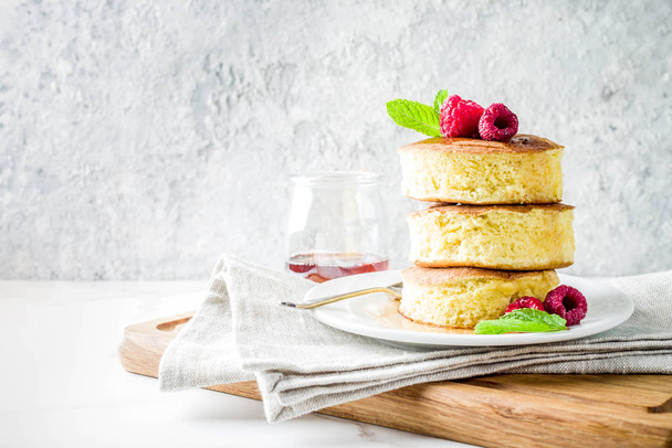 Trendy asian food, Fluffy Japan souffle pancakes, hotcakes with maple syrup and raspberry light concrete background copy space - Photo, Image