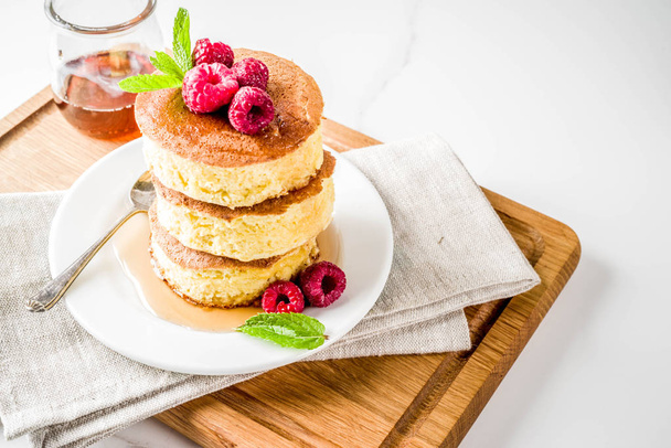 Trendy asian food, Fluffy Japan souffle pancakes, hotcakes with maple syrup and raspberry light concrete background copy space - Photo, Image