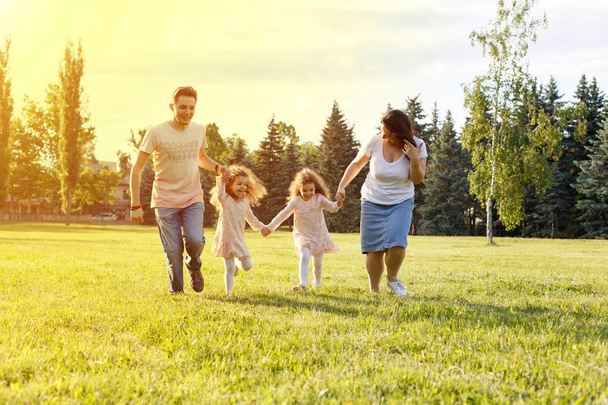 Lächelnde Familie läuft gemeinsam über Sommerfeld - Foto, Bild