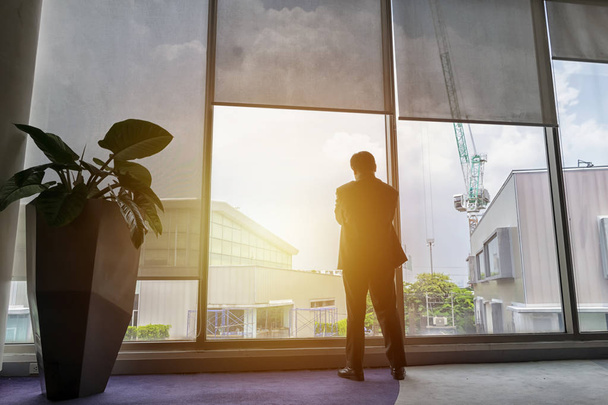Businessmen who are thinking about investing and expanding their business to support business growth. Standing next to a large glass window. - Photo, Image