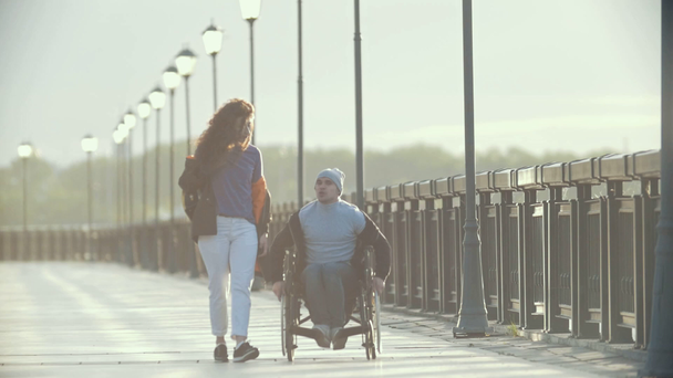 Ανάπηρο άνθρωπο σε αναπηρικό αμαξίδιο περπάτημα μαζί τη φίλη στην αποβάθρα - Πλάνα, βίντεο