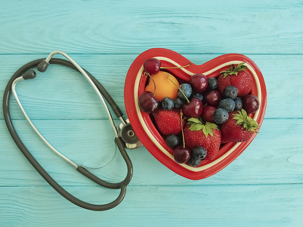 фруктова полуниця, чорниця, вишня, абрикос тарілка серце на синьому дереві, стетоскоп
 - Фото, зображення