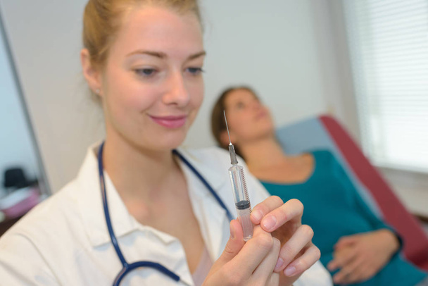 beautiful nurse is holding injection - Foto, Imagen