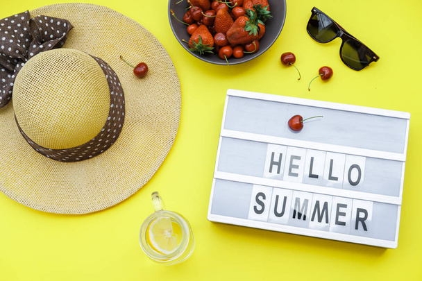 Hallo Sommer Blöcke Hintergrund auf dem gelben Tisch: Strohhut, Limo, Beeren. Draufsicht, flache Lage - Foto, Bild