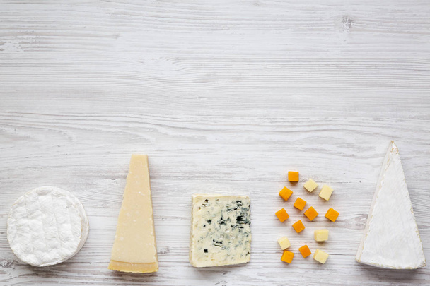 Valikoima erilaisia juustoja valkoisella puupohjalla kopiointitilalla. Ylhäältä, tasainen lay
. - Valokuva, kuva
