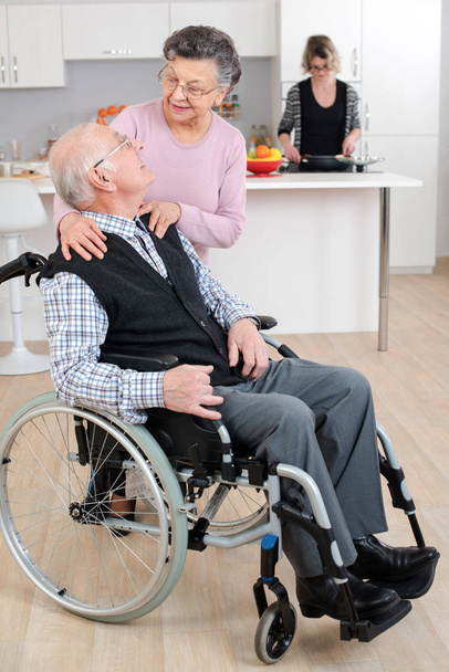 Elderly lady embracing husband in wheelchair - Fotografie, Obrázek