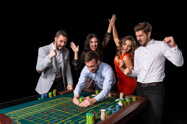 Adult group celebrating friend winning at roulette - 写真・画像