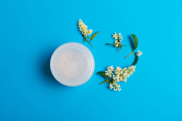Set of cosmetics on a blue background with white petals - Photo, Image