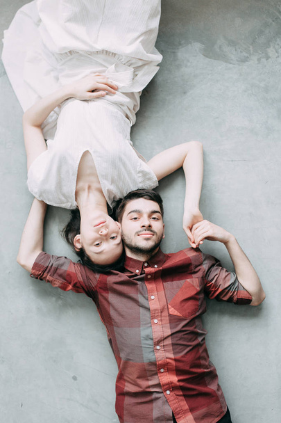 charismatic couple at a photo shoot in European style. Hugging and smiling looking at each other. The casual look and the light airy dress of the girl. the loft Studio, and a beautiful girl - Φωτογραφία, εικόνα