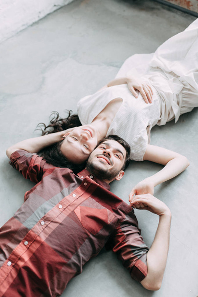 charismatic couple at a photo shoot in European style. Hugging and smiling looking at each other. The casual look and the light airy dress of the girl. the loft Studio, and a beautiful girl - Foto, Imagen