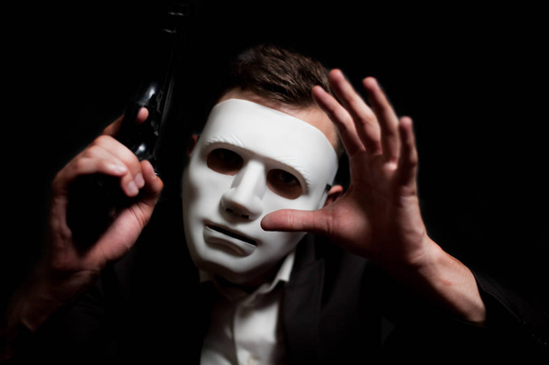 Close-up of a man in a white mask, holding a gun in his hand - Fotoğraf, Görsel