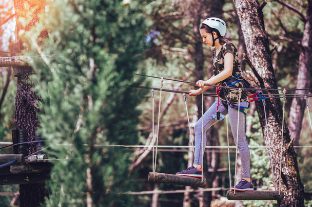 Happy school meisje genieten van activiteit in een klimmen avonturenpark op een zomerdag - Foto, afbeelding