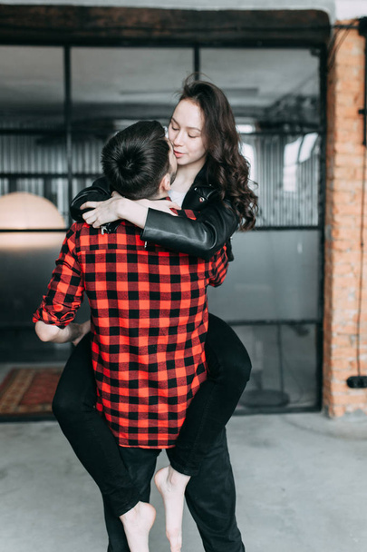 charismatic couple at a photo shoot in European style. Hugging and smiling looking at each other. The casual look and the light airy dress of the girl. the loft Studio, and a beautiful girl - Foto, afbeelding