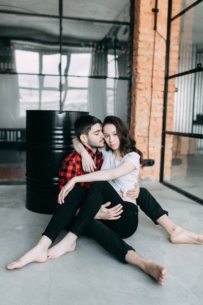 charismatic couple at a photo shoot in European style. Hugging and smiling looking at each other. The casual look and the light airy dress of the girl. the loft Studio, and a beautiful girl - Foto, Imagem