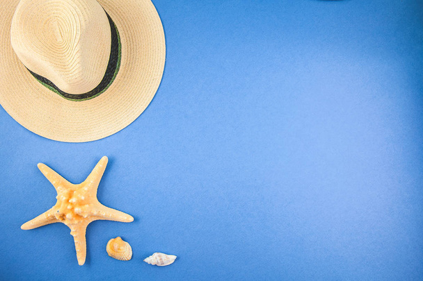 straw hat and starfish on a blue background Top view Copyspace - Zdjęcie, obraz