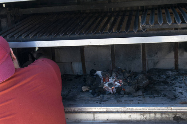 Человек сжигает уголь, чтобы приготовить барбекю
 - Фото, изображение