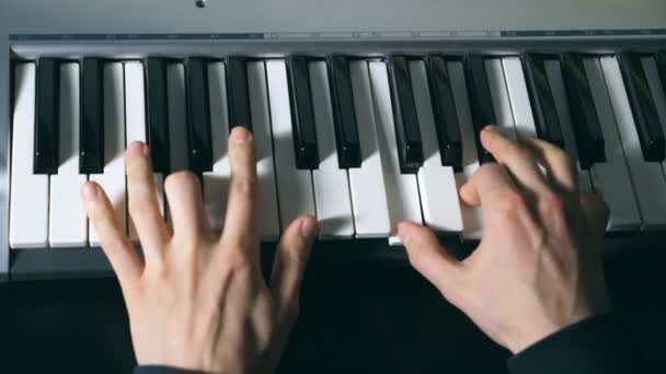Miesmuusikon kädet soittavat syntetisaattorissa. Miesten kädet soittavat yksin musiikkia tai uutta melodiaa. Sulje pianistin sormet pianonsoiton kohdalla. Hidastettuna Ylhäältä eristetty kuva
 - Materiaali, video
