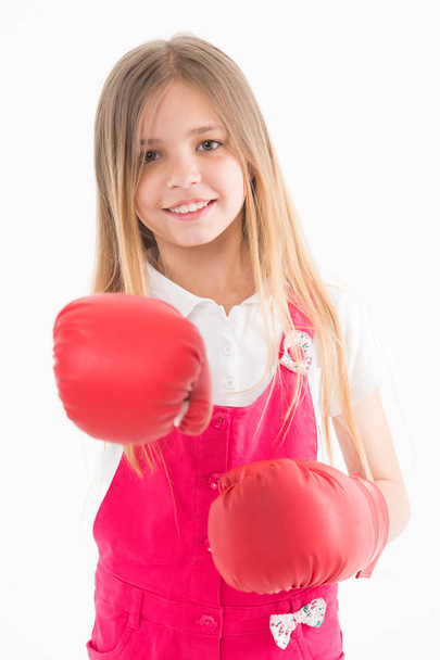 Girls power concept. Girl on smiling face posing with boxing gloves, isolated on white background. Girl likes boxing and sporty lifestyle. Kid girl with long hair knows how to defend herself - Fotó, kép