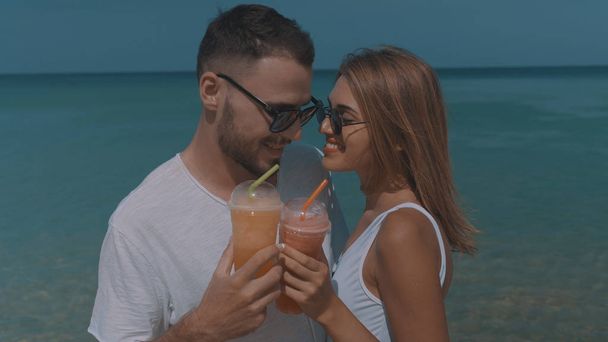 日当たりの良い夏の休暇中に熱帯のビーチで飲むジュースの幸せカップル - 写真・画像