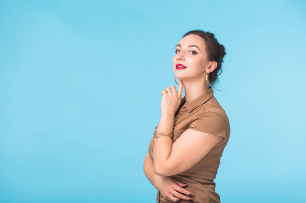 Confident young woman standing over blue background. - Foto, afbeelding