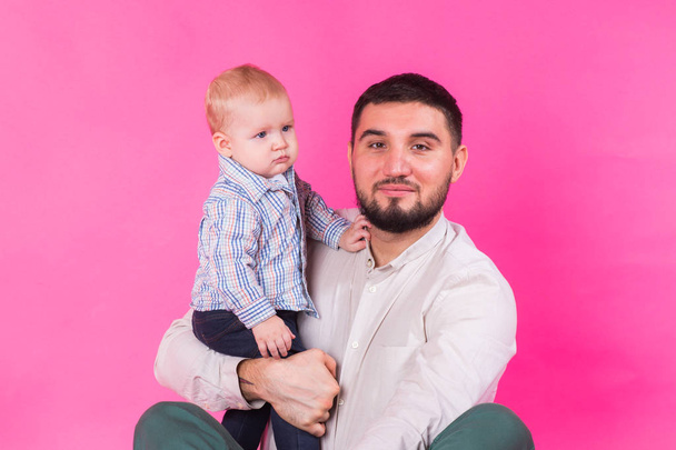 happy father with a baby son isolated on a pink background - Fotó, kép