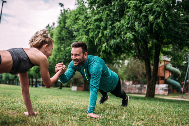 young man and woman doing push-ups outdoor - Foto, Imagen