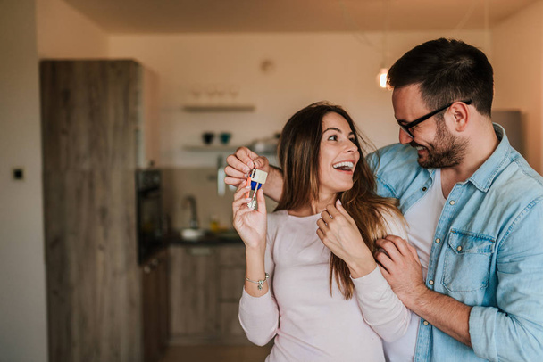 junges glückliches Paar zeigt Schlüssel für neues Zuhause - Foto, Bild