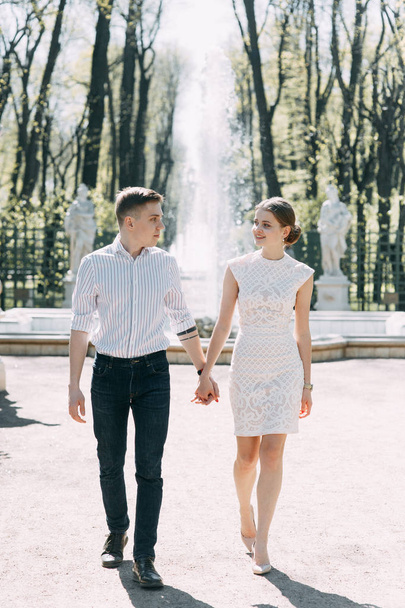 愛情と幸せの晴れた日に公園の美しい若いカップル。歩くし、一緒に笑います。自然に撮影前の結婚式。有名人のような服でエレガントなスタイル - 写真・画像